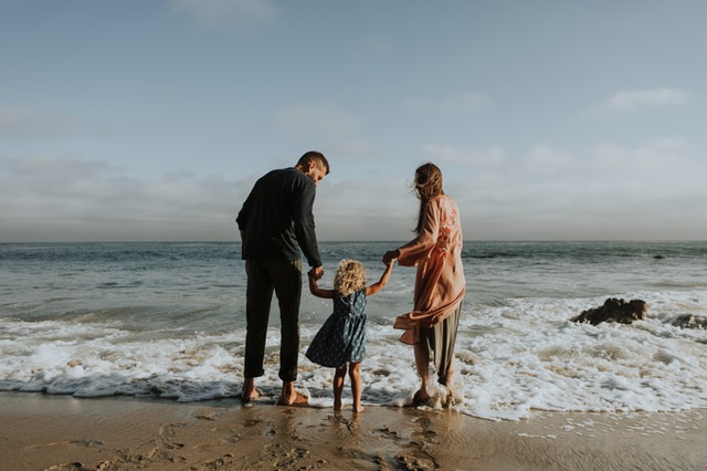 Child with parents barefoot on beach